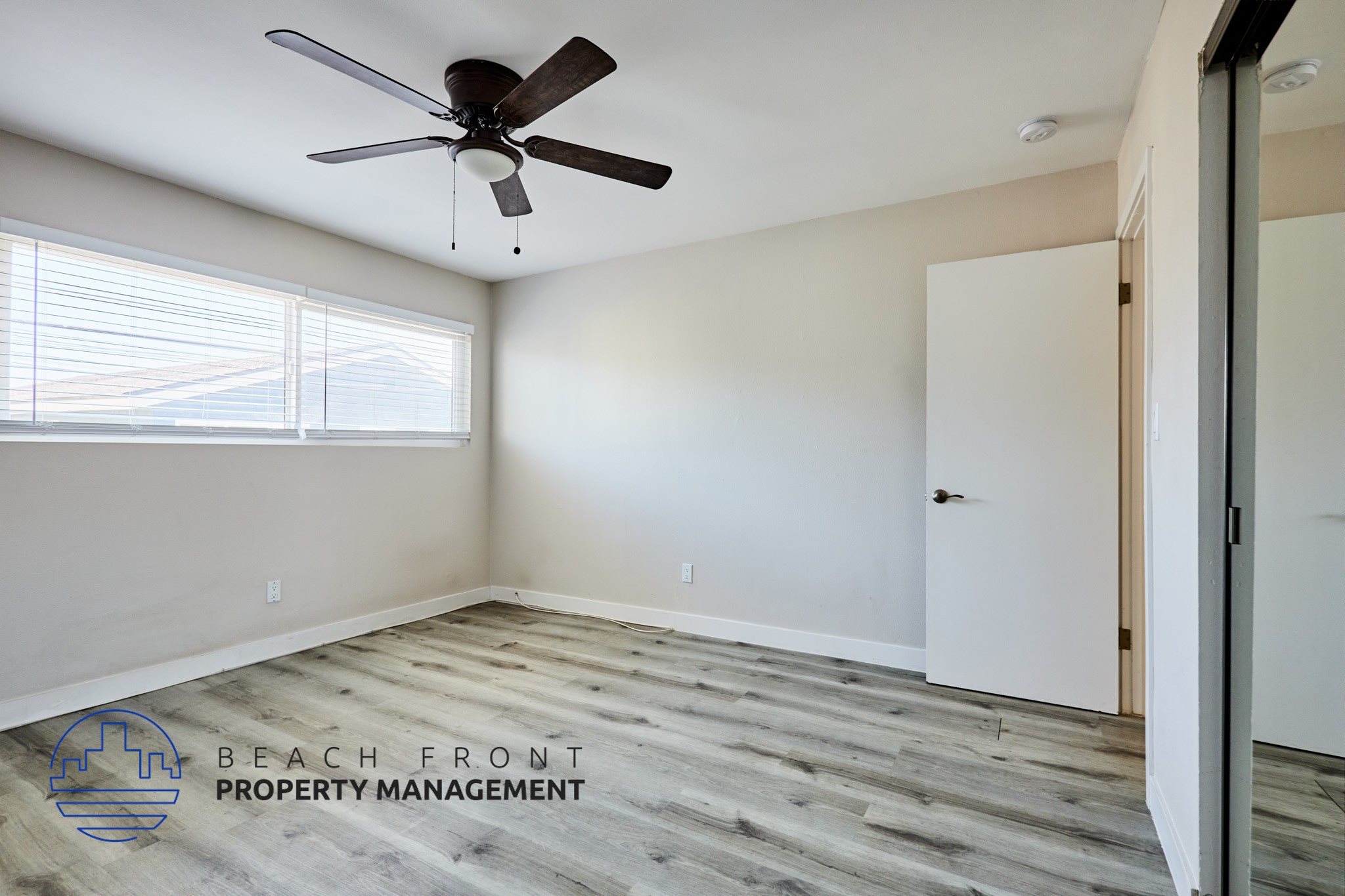 A room with a ceiling fan and wooden flooring.